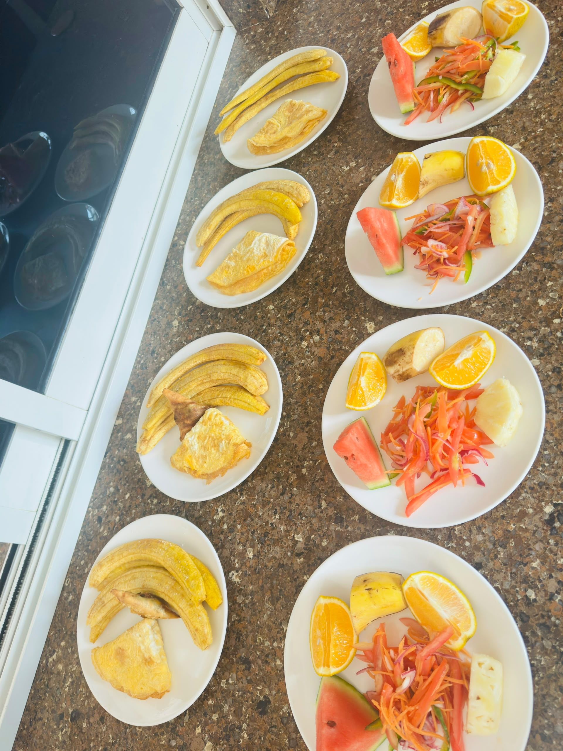 Uma bancada de cozinha com diversos itens de pequeno-almoço, incluindo bananas, ovos e fruta.