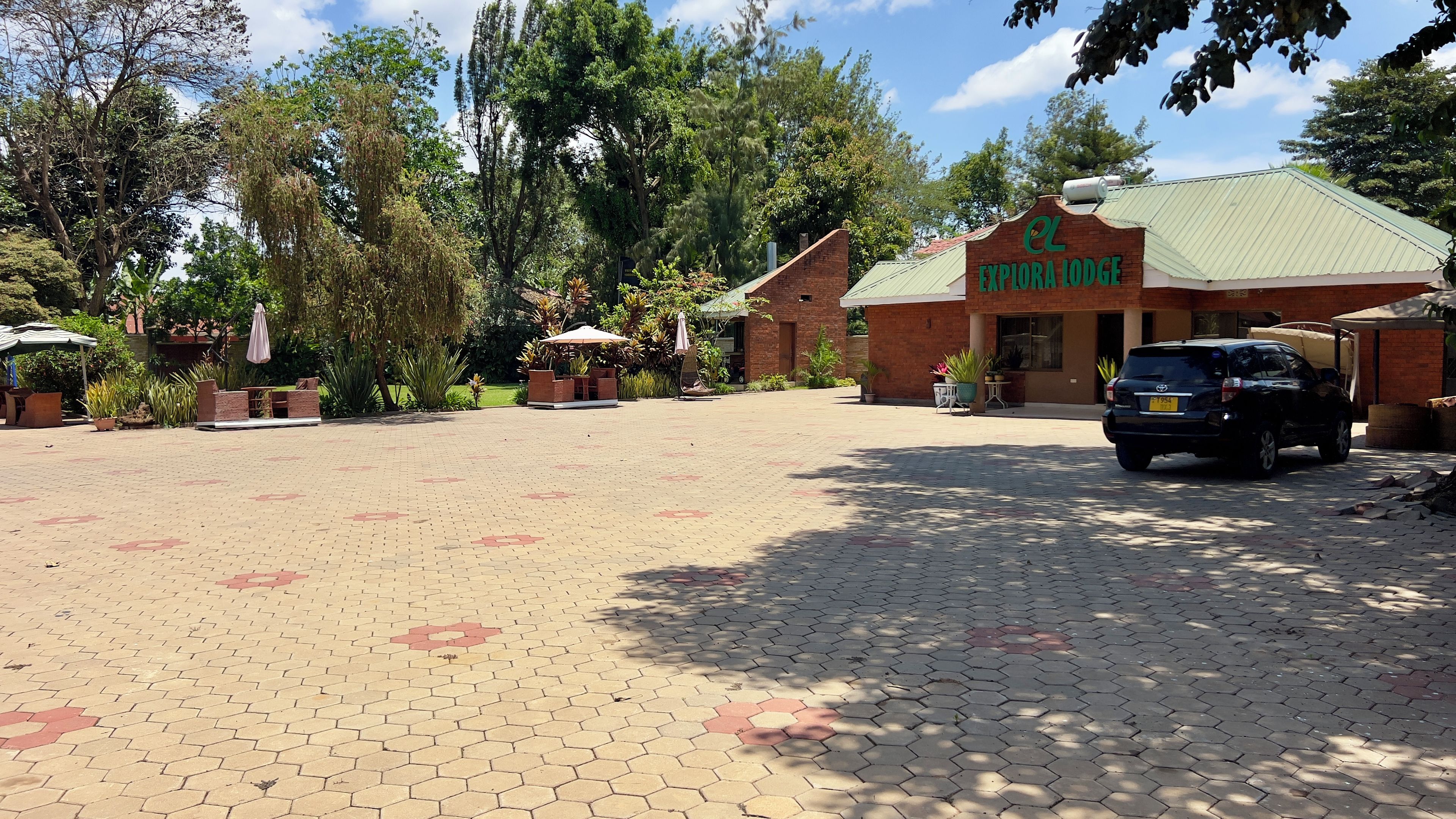 Un área de acceso pavimentada con un cartel que dice 'Explora Lodge' y un vehículo estacionado.