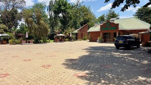 Une zone d’entrée dallée, avec un panneau indiquant « Explora Lodge » et un véhicule garé.