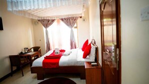 Une chambre d’hôtel avec un lit, un bureau et une armoire.