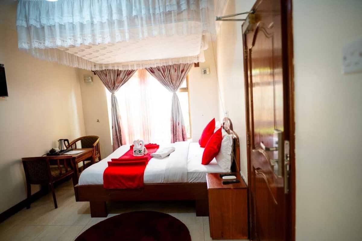 Une chambre d’hôtel avec un lit, un bureau et une armoire.