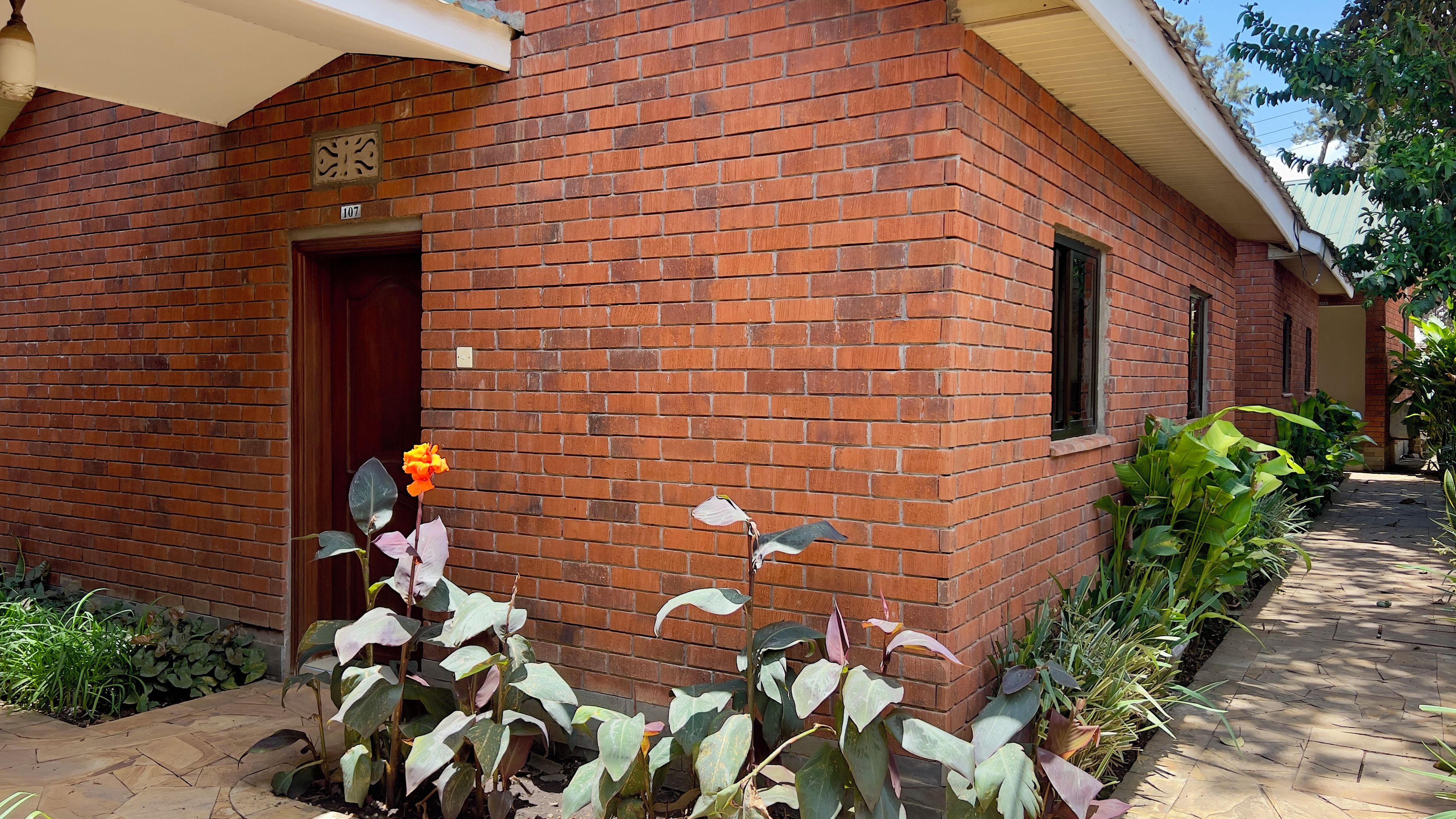 A brick building with a door and windows, surrounded by greenery.