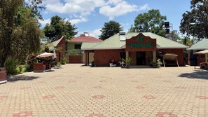 A brick building with a green roof and a sign that reads 'EXPLORA LODGE'. - Explora Lodge (Arusha)