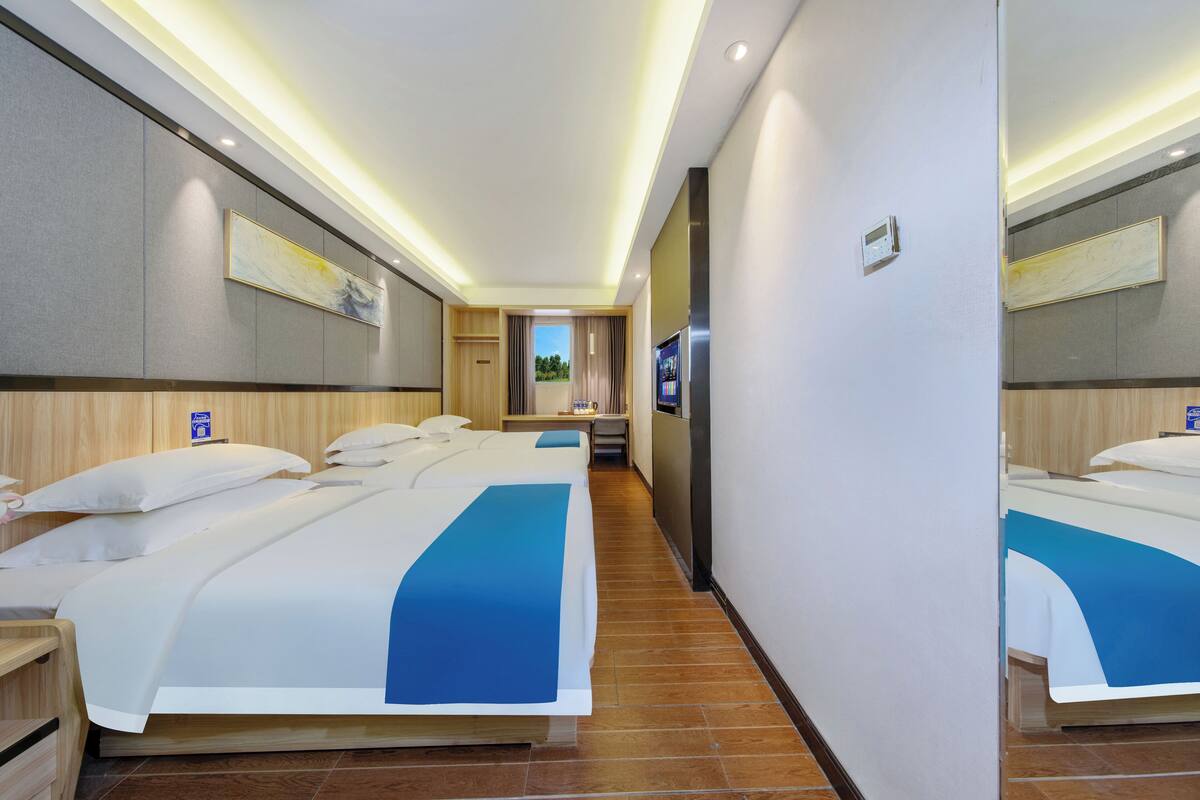 Habitación de hotel con dos camas, televisión, minibar y baño con ducha e inodoro.