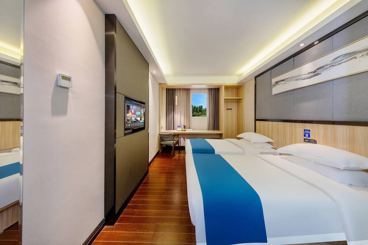 Habitación de hotel con cama, escritorio, televisión y vistas al exterior.