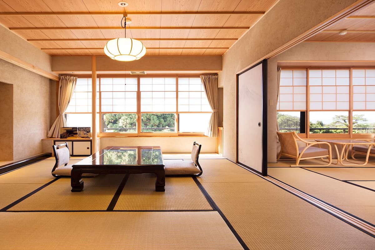 A traditional Japanese room with tatami flooring, a low table, and chairs.