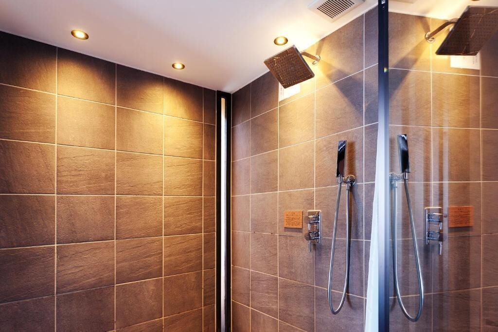 A modern bathroom with a glass-enclosed shower, tiled walls, and built-in lighting.