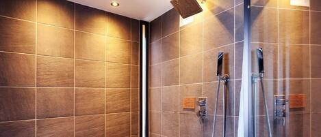 Un baño moderno con ducha de vidrio, paredes de azulejos e iluminación empotrada.