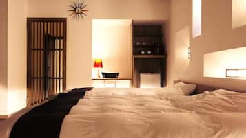 Un dormitorio con una cama grande, un escritorio con silla, un armario y una lámpara fijada a la pared.