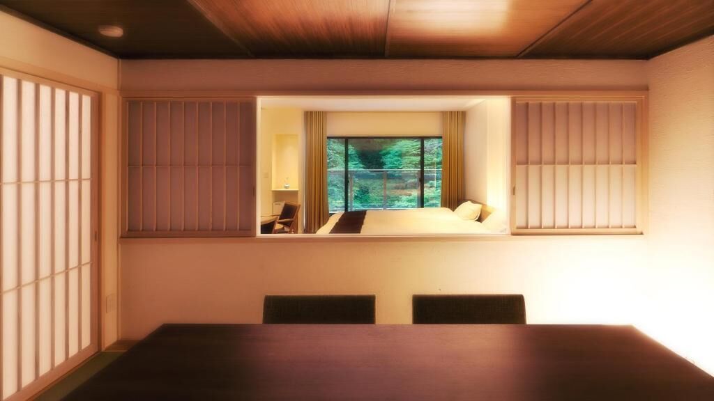 A hotel room with a large bed, a small desk, and a view of greenery through a window.