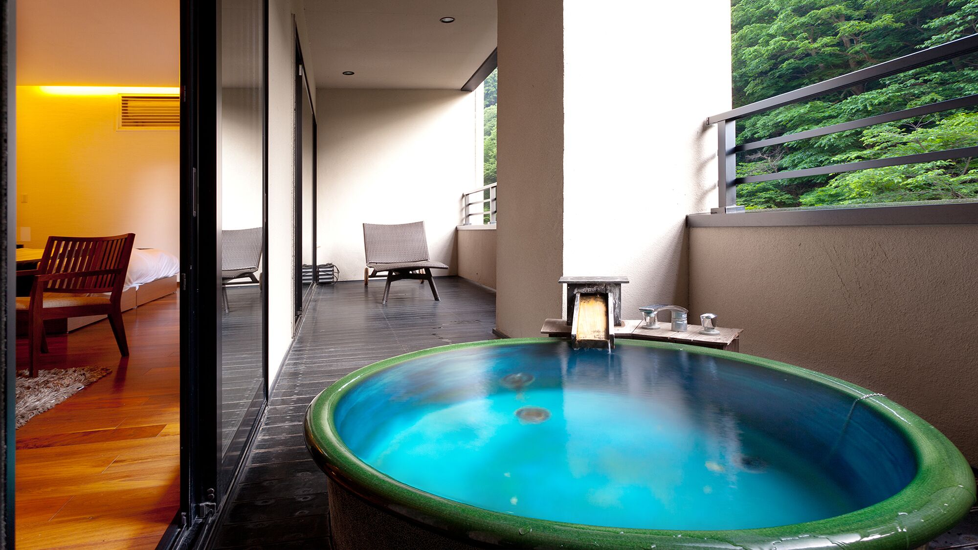 A spa area with a hot tub, wooden flooring, and a view of greenery.
