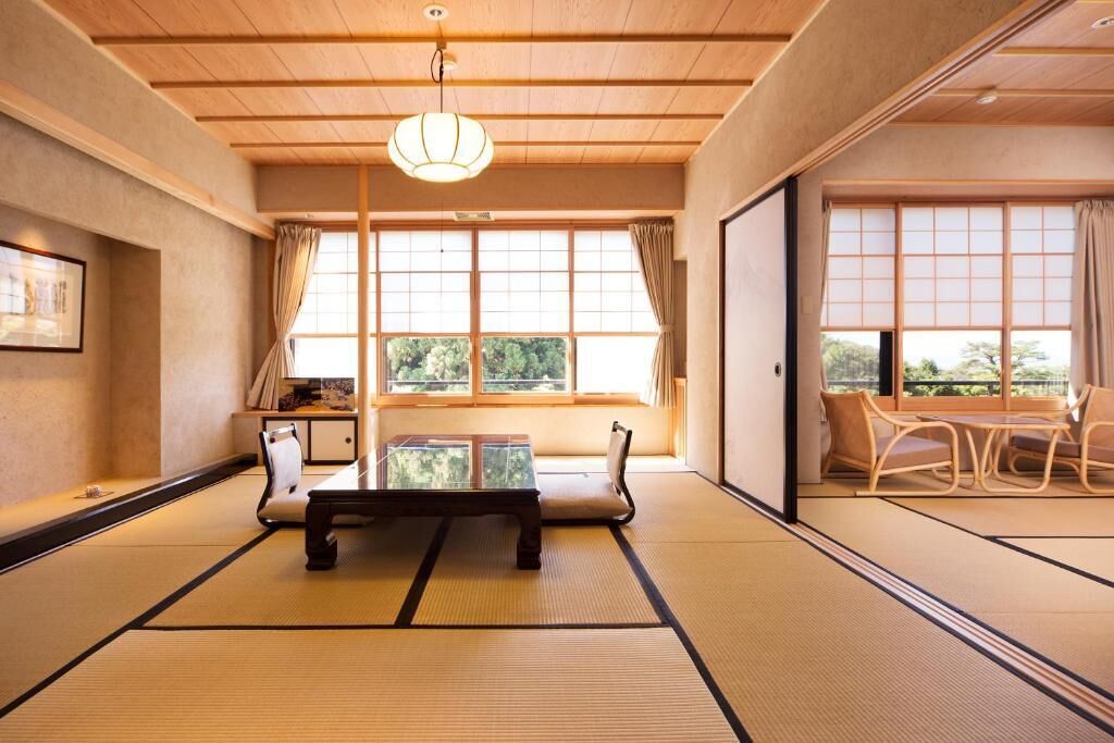 A traditional Japanese room with tatami flooring, a low table, and a sliding door leading to a dining area.