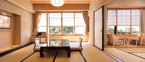 A traditional Japanese room with tatami flooring, a low table, and a sliding door leading to a dining area.