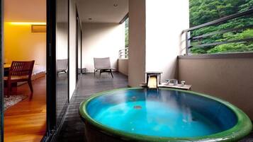 A modern hotel room with a large window, a small balcony, and a hot tub.