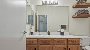 A bathroom with wooden cabinets, a white sink, a mirror, and a towel rack. - Indulge in this beautiful New Mexico home located in Southwest Albuquerque (Albuquerque)
