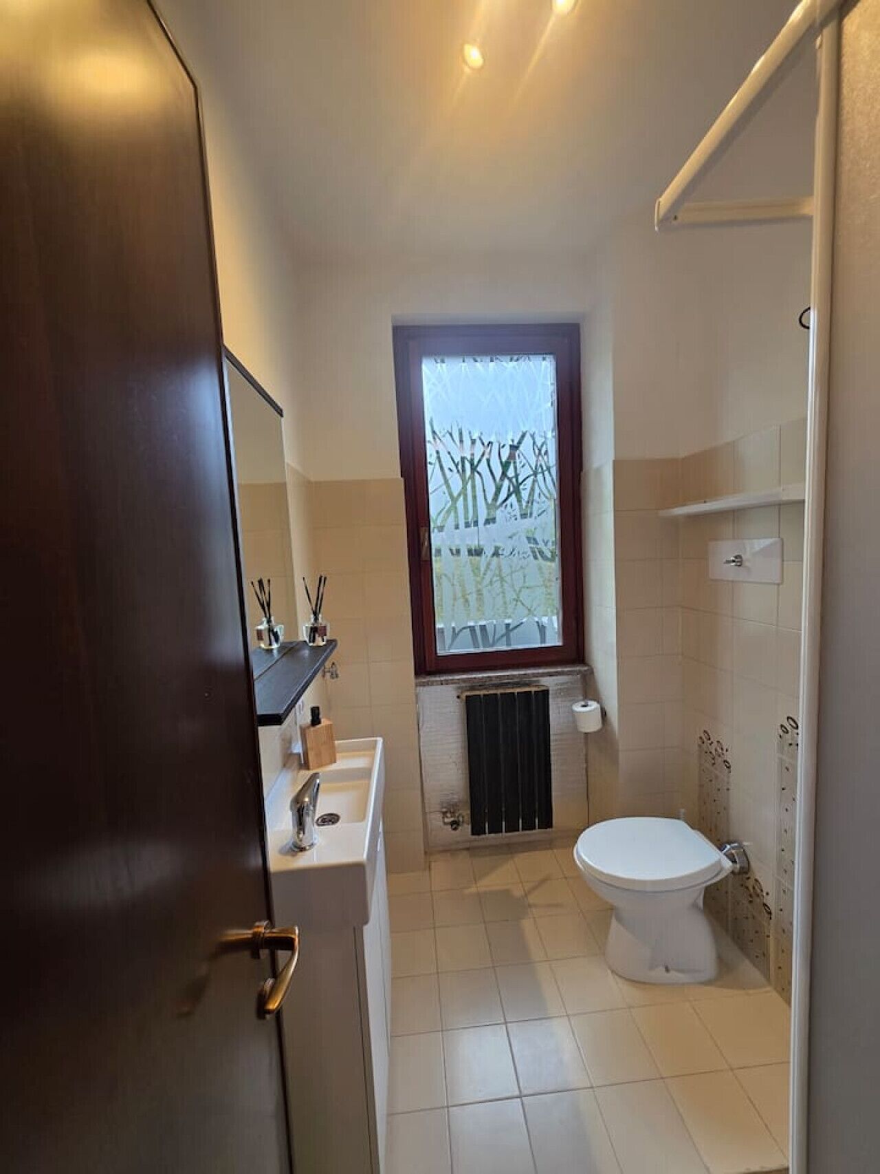 A bathroom with a toilet, sink, and window.