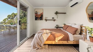 A bedroom with a wooden bed, a large window, and a balcony.