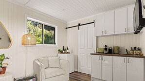 A modern kitchen with white cabinets, a wooden countertop, and a window with a view of greenery.