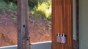 A wooden structure with a metal fixture, possibly a shower, and a green door with a lock.