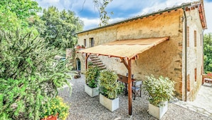 A rustic building with a covered patio, potted plants, and a staircase leading to an upper level. - Tenuta della Selva - Castellaccio 7 (Monteroni d'Arbia)