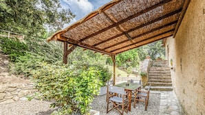 A covered outdoor seating area with a table and chairs, surrounded by greenery and a stone staircase. - Tenuta della Selva - Castellaccio 7 (Monteroni d'Arbia)