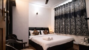 Ein Hotelzimmer mit Bett, Sessel, Nachttisch, Lampe und Wandleuchte.