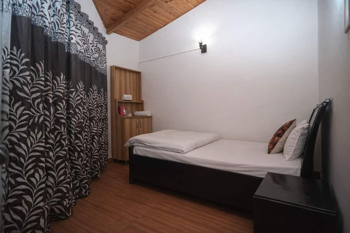 A bedroom with a bed, wooden wardrobe, and a nightstand.