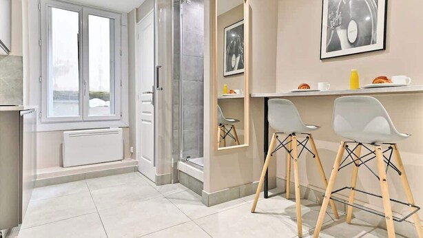 Et moderne badeværelse med bruser, toilet og håndvask. Der er et vindue med naturligt lys, og et billede i ramme på væggen.