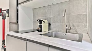 Et moderne køkken med en indbygget vask, kaffemaskine og en rød brandslange.