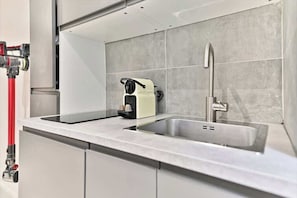 Een moderne keuken met een inbouwspoelbak, een koffiezetapparaat en een rode brandslang.