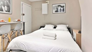 Et hotelværelse med seng, skrivebord, stole og et lille bord.