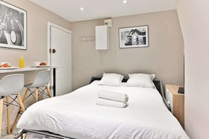 Een hotelkamer met een bed, een bureau, stoelen en een kleine tafel.