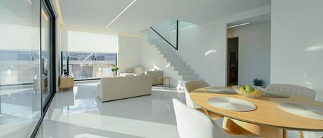 Un espace de vie moderne comprenant un coin repas, un escalier et une vue dégagée grâce à de grandes fenêtres.