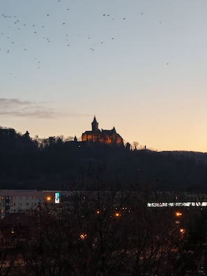 A castle-like building on a hill with a clear sky and a few birds flying in the distance.