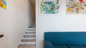 Un escalier menant à un palier, un canapé bleu et une œuvre d’art abstrait accrochée au mur.