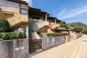A multi-story building with stone steps, a gated entrance, and a clear sky. - GuestHost - The house is located in the heart of the residential and tourist district of Porto Corallo, a hamlet of the municipality of Villaputzu, on the south-eastern coast of Sardinia. The area is known for its natural beauty, tranquility and the pres (Porto Tramatzu)