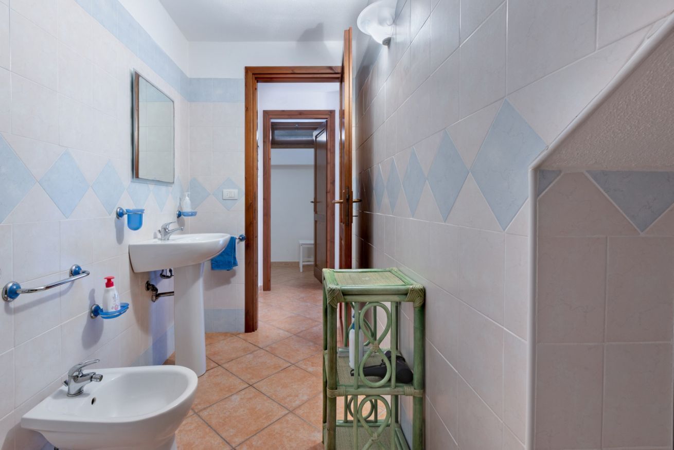 A bathroom with a sink, mirror, and a green shelf.
