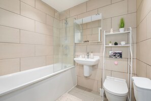 A modern bathroom with a bathtub, a sink, a toilet, and a glass-enclosed shower. - Apartment - Sleeps 3 - Royalvictoriastation 5mins (London)