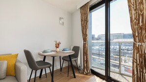 Ein modernes Wohnzimmer mit Essbereich, großen Fenstern und Blick auf die Stadtlandschaft.