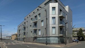 Ein modernes mehrstöckiges Gebäude mit Balkonen, großen Fenstern und blauem Himmel.