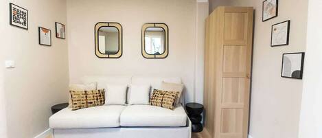 A modern living room with a white sofa, two mirrors, and a wooden door.