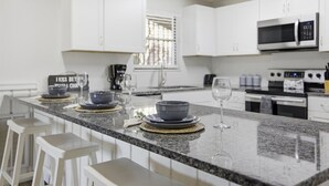 Una cocina moderna con armarios blancos, encimera de granito y microondas integrado.