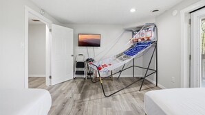 Una habitación con cama, televisión, aro de baloncesto y escalera.