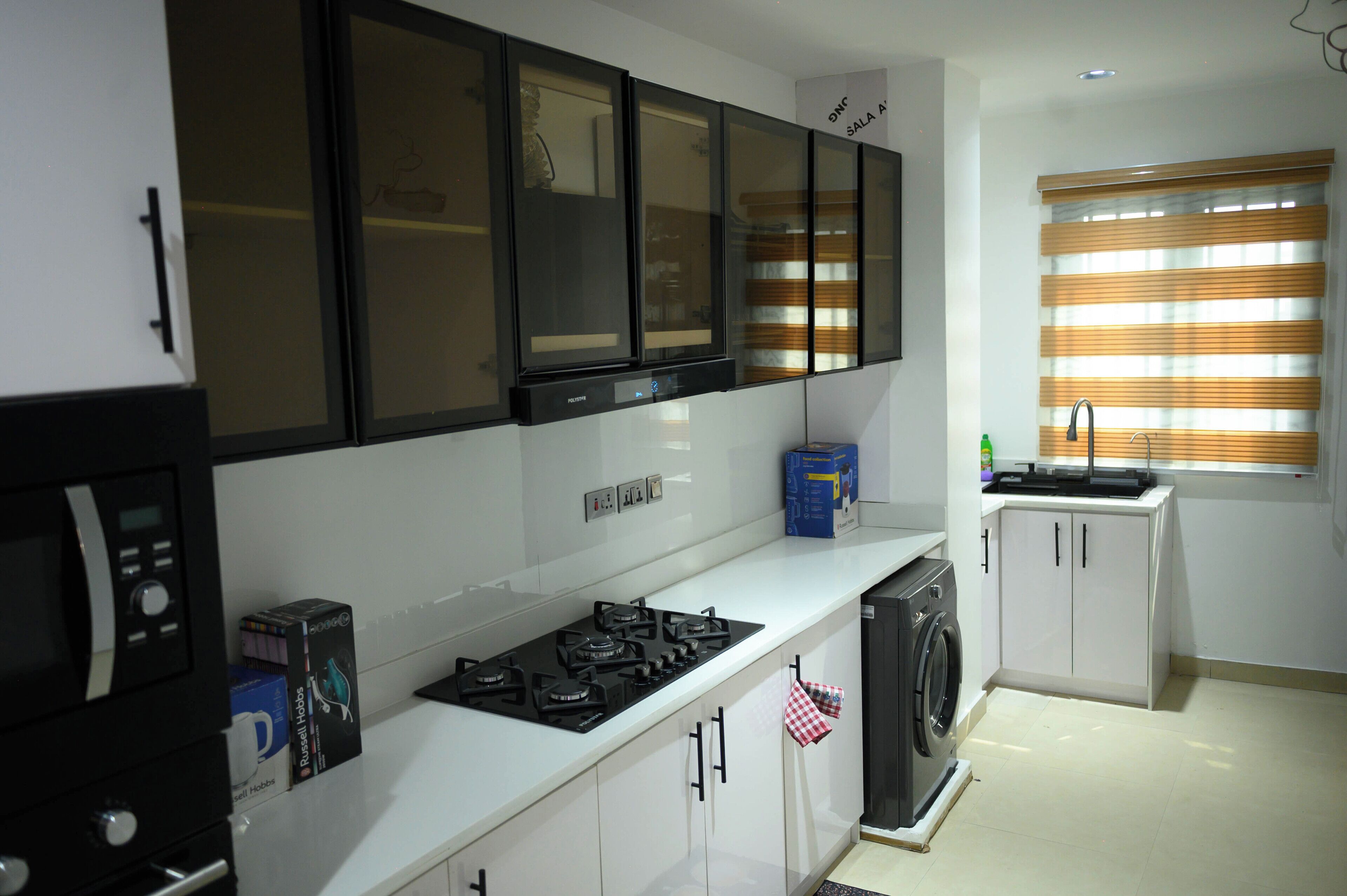 A kitchen with white cabinets, a black stove, and a washing machine.