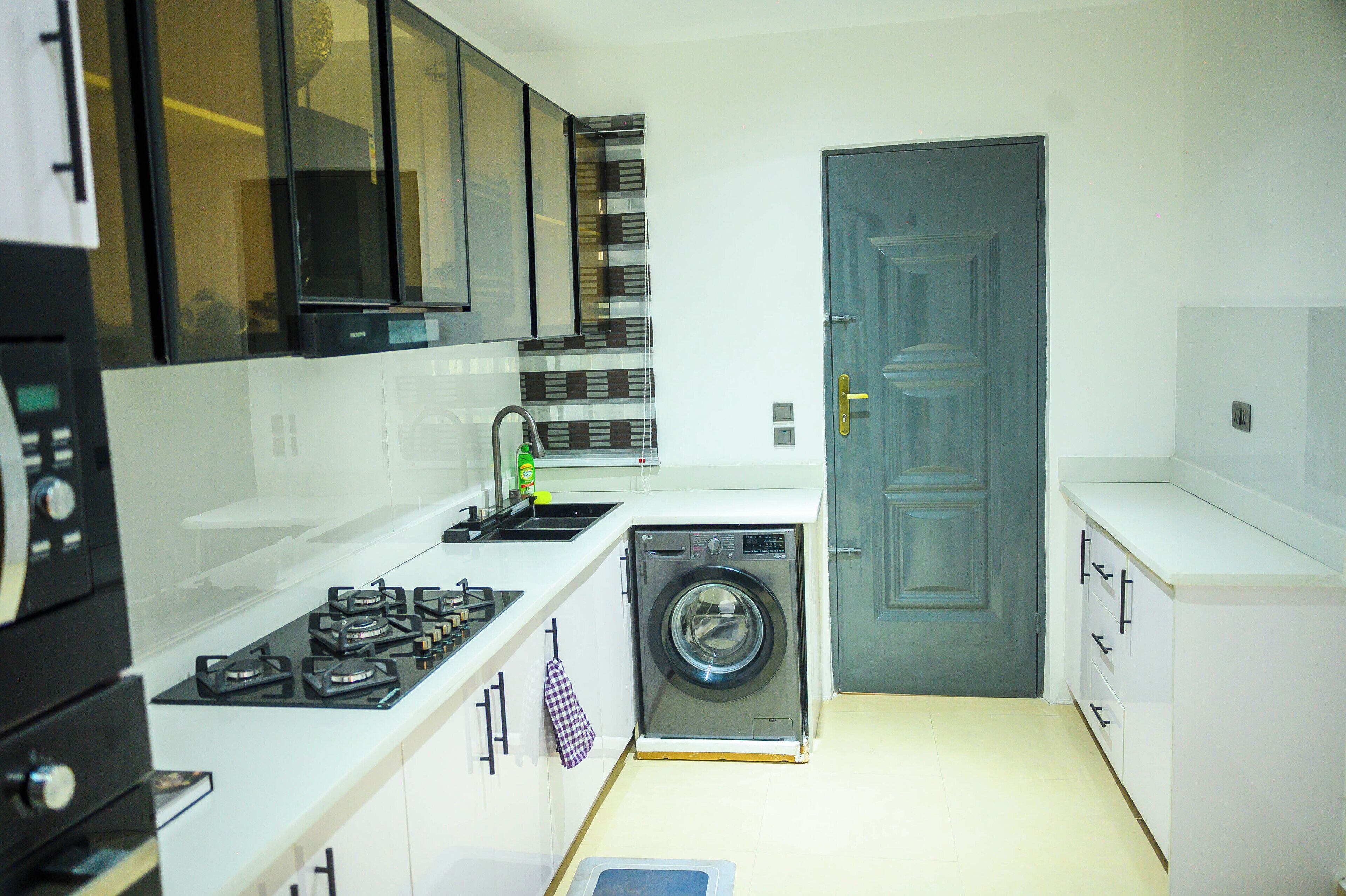 A compact kitchen with a gas stove, a washing machine, and white cabinetry.