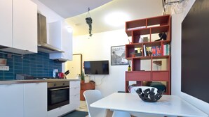A modern kitchen with white cabinets, a built-in oven, and a dining area with a white table and chairs. - Le finestre di NoLo, city pad for two in Milan (Milano)