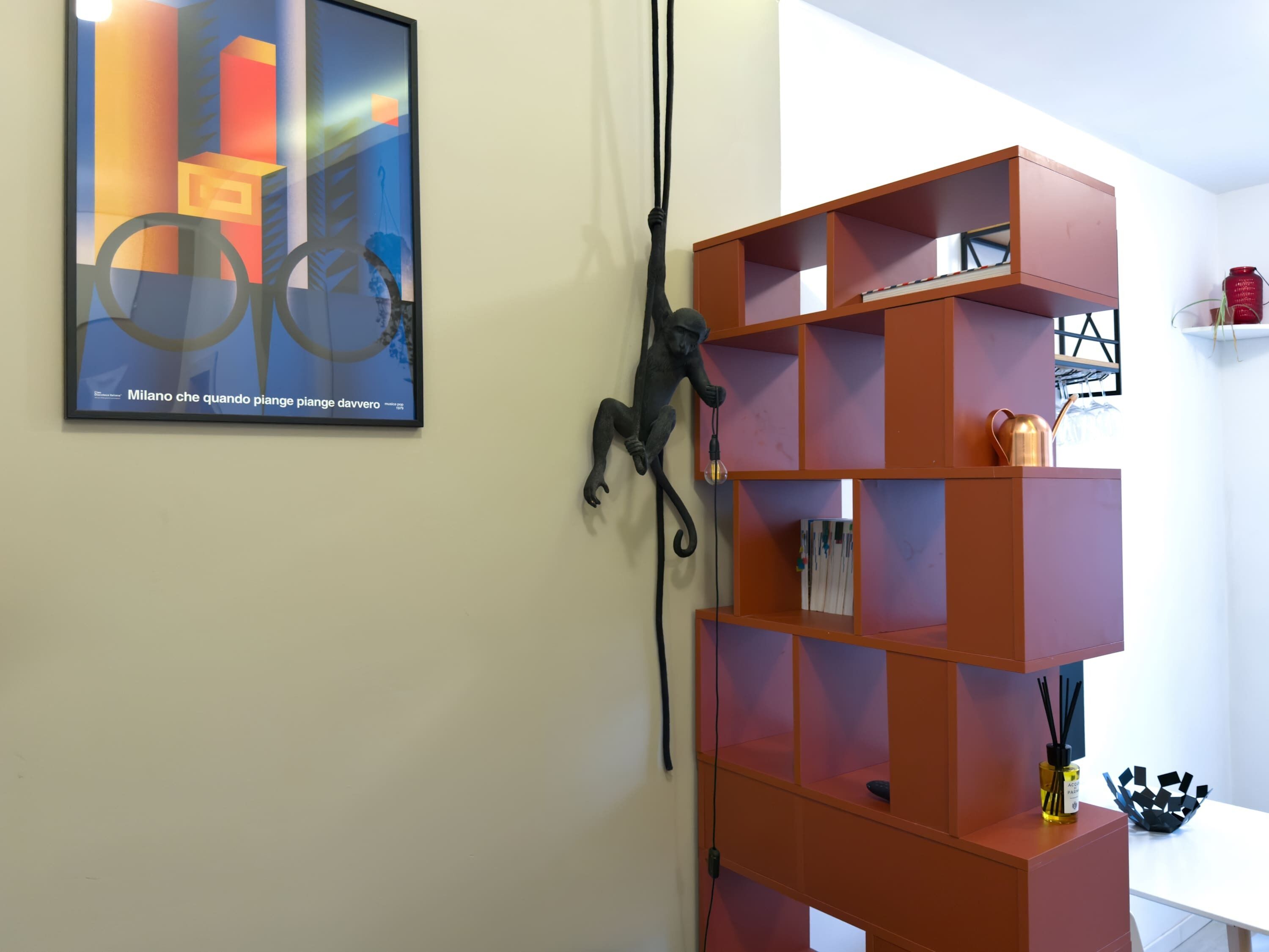 A room with a framed abstract painting, a red shelving unit, and a black sculpture.