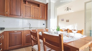 Une cuisine avec des meubles de rangement en bois, une table à manger dressée pour quatre personnes et un lustre.
