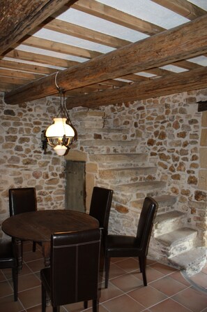 Un mur en pierre rustique, un plafond en bois et une cheminée en pierre.