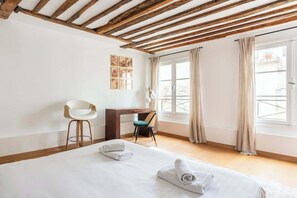 Ein Hotelzimmer mit Bett, Schreibtisch, Stuhl und einem Vorhangfenster.